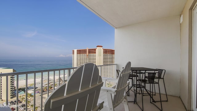 balcony with a water view and a view of the beach