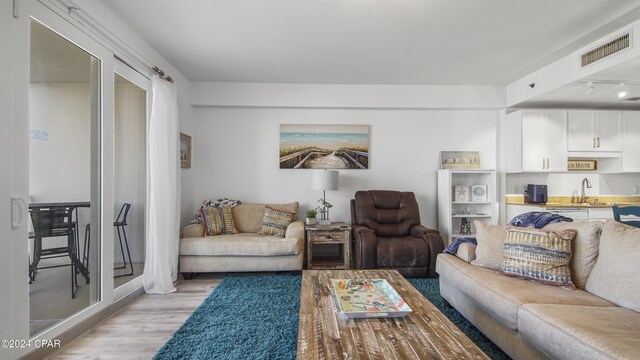 living room featuring light wood-type flooring, sink, and rail lighting