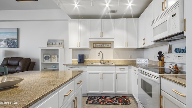 kitchen with sink, light stone counters, white cabinets, and white appliances