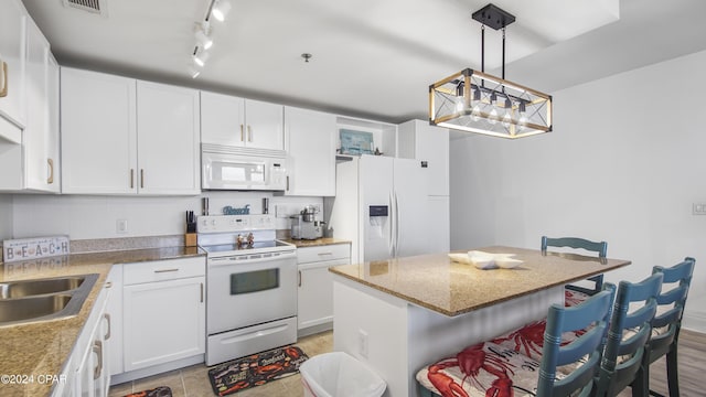 kitchen featuring white cabinetry, hanging light fixtures, white appliances, and a center island