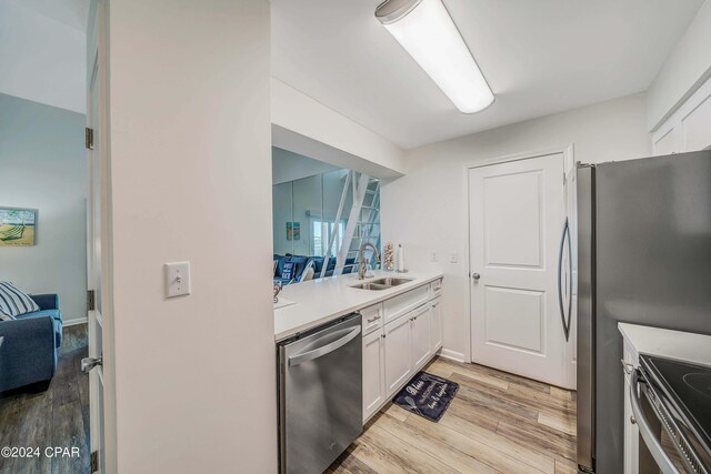 kitchen with white cabinetry, stainless steel dishwasher, range, light hardwood / wood-style floors, and sink