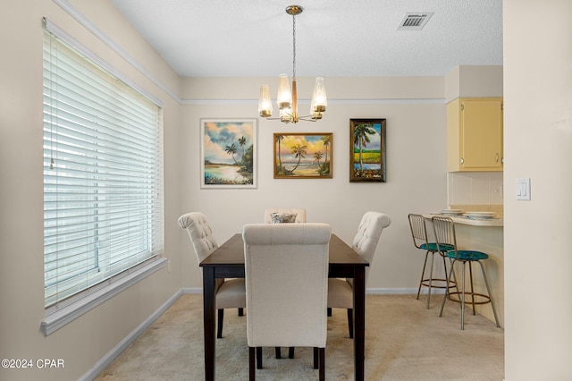 dining area with a textured ceiling, light carpet, and a chandelier