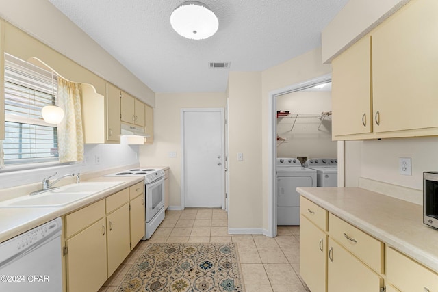 kitchen featuring a textured ceiling, light tile patterned floors, white appliances, sink, and washer and clothes dryer