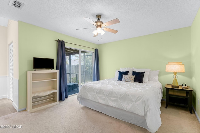 bedroom featuring ceiling fan, access to outside, a textured ceiling, and light colored carpet