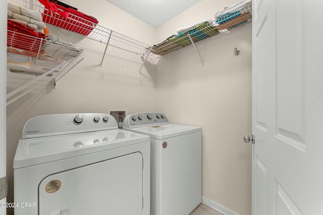 clothes washing area featuring a textured ceiling and washer and clothes dryer