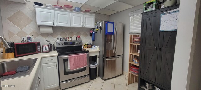 kitchen featuring appliances with stainless steel finishes, light tile patterned floors, sink, white cabinetry, and backsplash