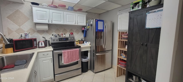 kitchen featuring sink, stainless steel appliances, white cabinets, light tile patterned flooring, and decorative backsplash