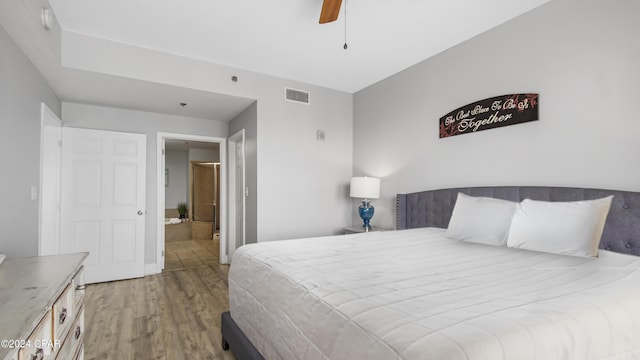 bedroom featuring visible vents, a ceiling fan, ensuite bathroom, and wood finished floors