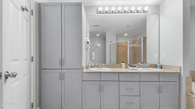 bathroom with an enclosed shower and dual vanity