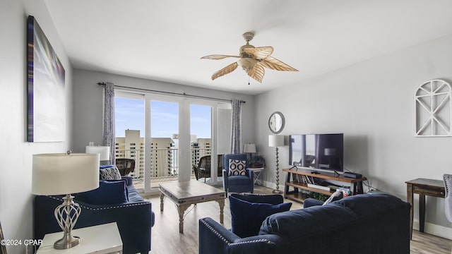 living area featuring baseboards, a ceiling fan, and wood finished floors