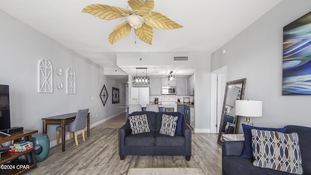 living room with visible vents, baseboards, a ceiling fan, and light wood-style flooring