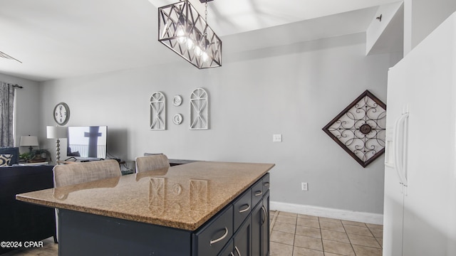 kitchen with hanging light fixtures, white refrigerator with ice dispenser, a kitchen island, light tile patterned flooring, and light stone counters