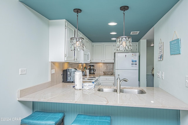 kitchen featuring sink, a kitchen breakfast bar, kitchen peninsula, white appliances, and white cabinets