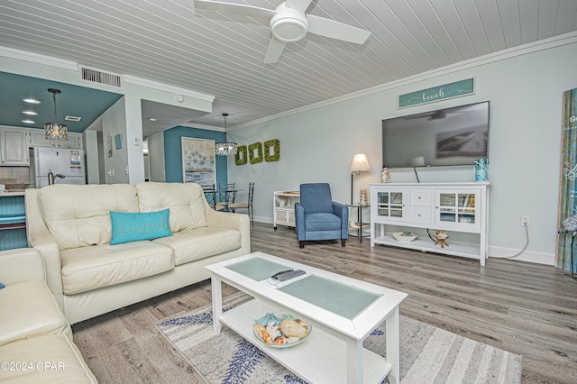 living room with crown molding, wood-type flooring, and ceiling fan with notable chandelier