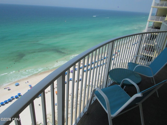 balcony with a water view and a view of the beach