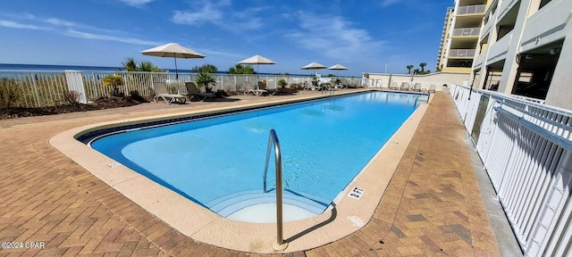 view of pool with a patio and a water view