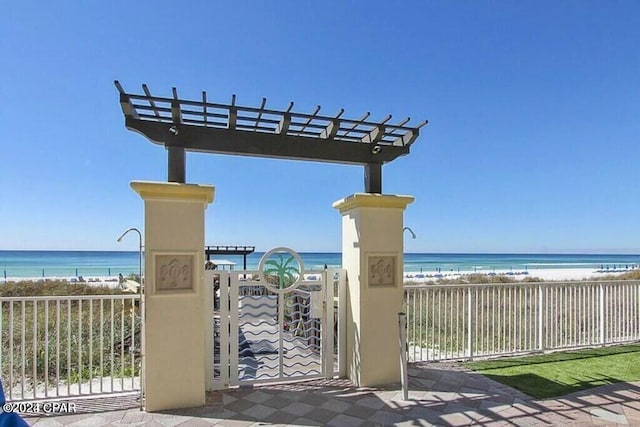 view of community featuring a water view, a pergola, and a view of the beach