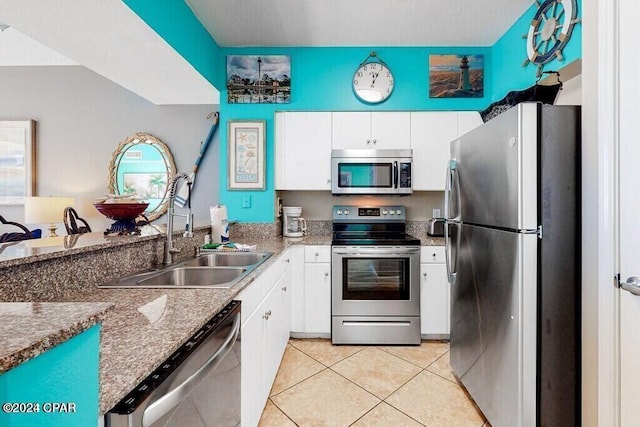 kitchen with white cabinetry, stainless steel appliances, light tile patterned floors, and sink