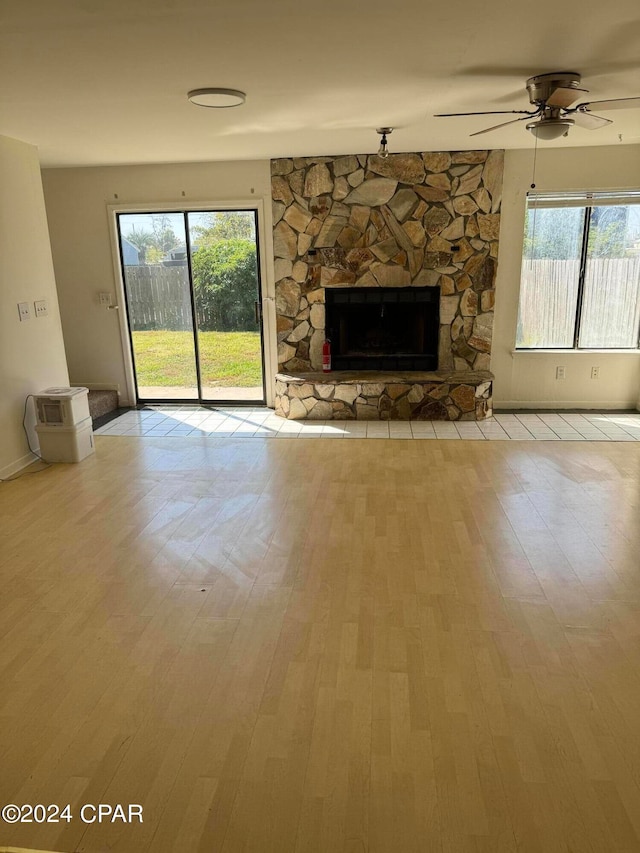 unfurnished living room with a wealth of natural light, a stone fireplace, and light hardwood / wood-style floors