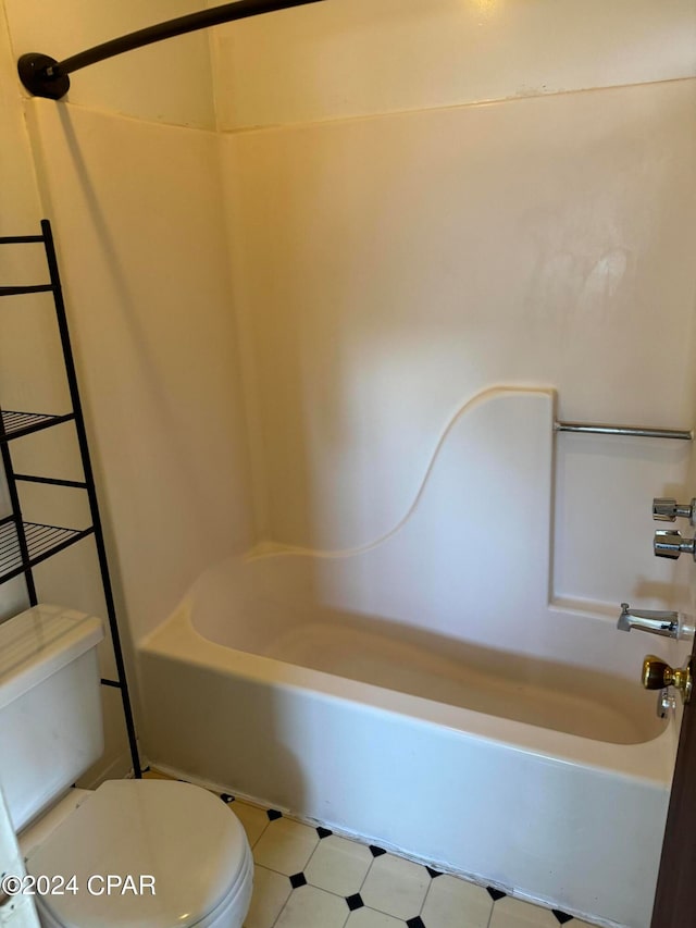 bathroom featuring toilet, tile patterned floors, and  shower combination