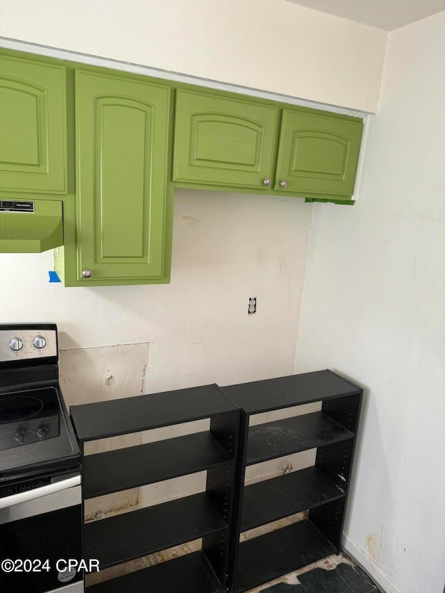 kitchen with electric stove, exhaust hood, and green cabinetry