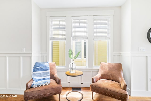 sitting room with a wainscoted wall, visible vents, a decorative wall, and wood finished floors