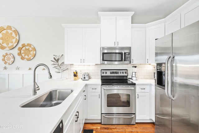 kitchen with stainless steel appliances, backsplash, a sink, and white cabinetry