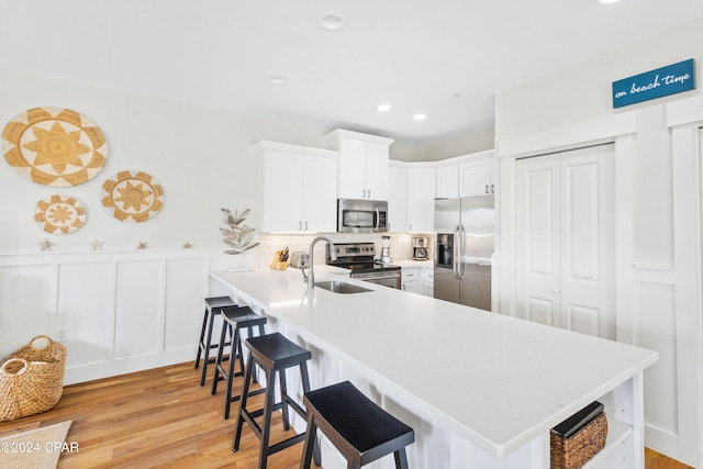 kitchen featuring appliances with stainless steel finishes, a breakfast bar area, a peninsula, light countertops, and white cabinetry