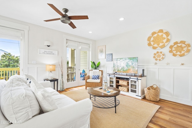 living room with recessed lighting, wainscoting, light wood-style flooring, and a decorative wall