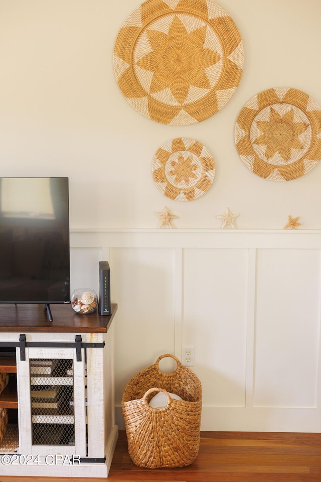 interior details with wainscoting, a decorative wall, and wood finished floors