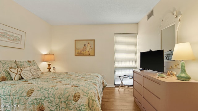 bedroom featuring light hardwood / wood-style flooring and a textured ceiling