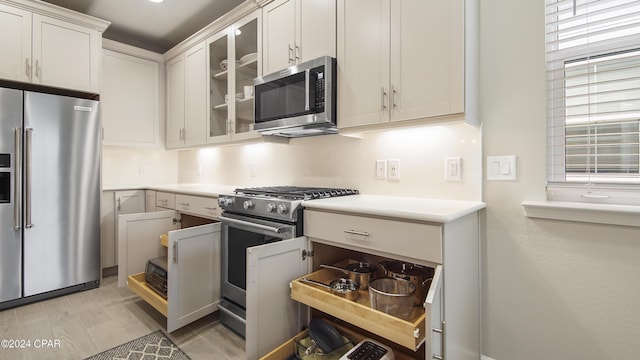 kitchen with appliances with stainless steel finishes, white cabinets, and light wood-type flooring