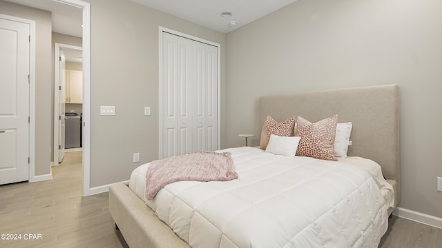 bedroom with washer / clothes dryer, wood-type flooring, and a closet