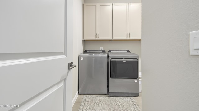 clothes washing area featuring cabinets and washing machine and clothes dryer