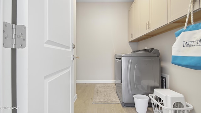 laundry area featuring cabinets, independent washer and dryer, and light hardwood / wood-style floors