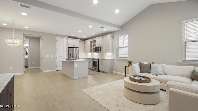 living room with lofted ceiling, a chandelier, and light hardwood / wood-style flooring