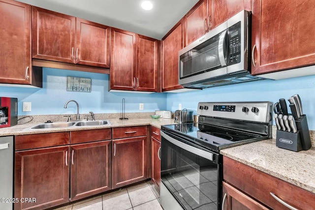 kitchen with light stone counters, stainless steel appliances, sink, and light tile patterned floors