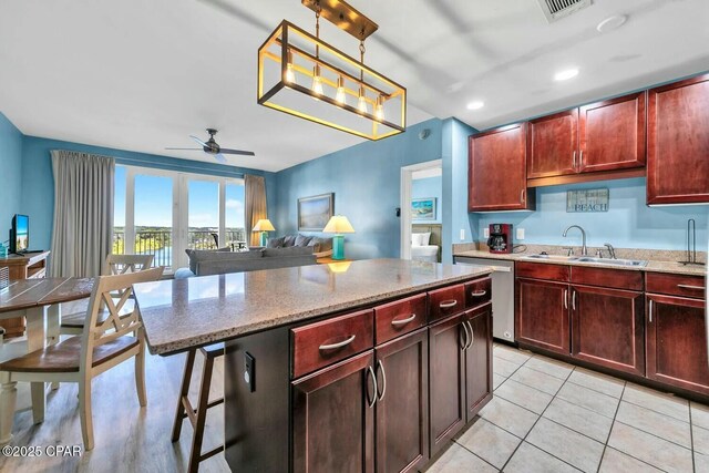 kitchen featuring sink, ceiling fan, a center island, a kitchen bar, and decorative light fixtures