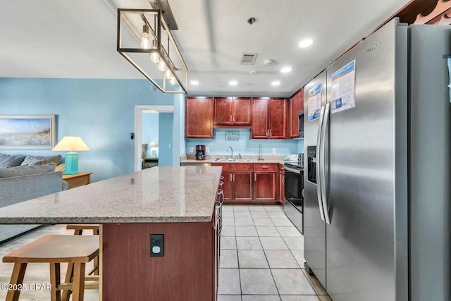 kitchen featuring sink, appliances with stainless steel finishes, a center island, light stone counters, and light tile patterned flooring