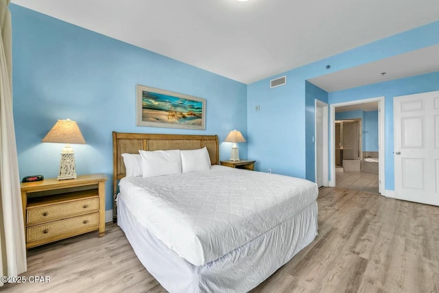 bedroom with connected bathroom and light hardwood / wood-style floors