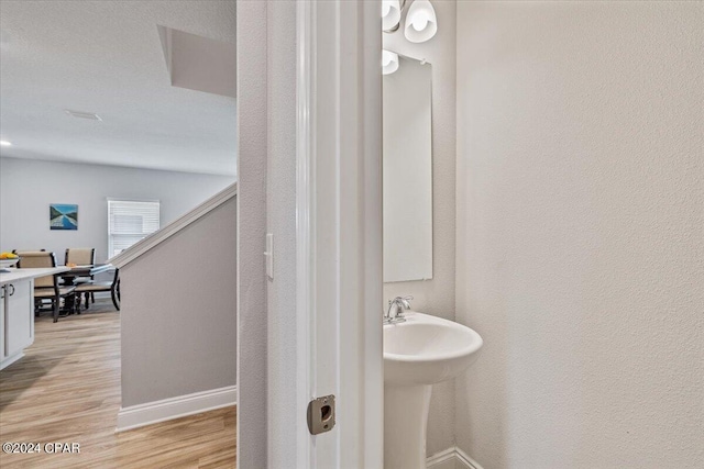 bathroom with a textured wall, baseboards, and wood finished floors