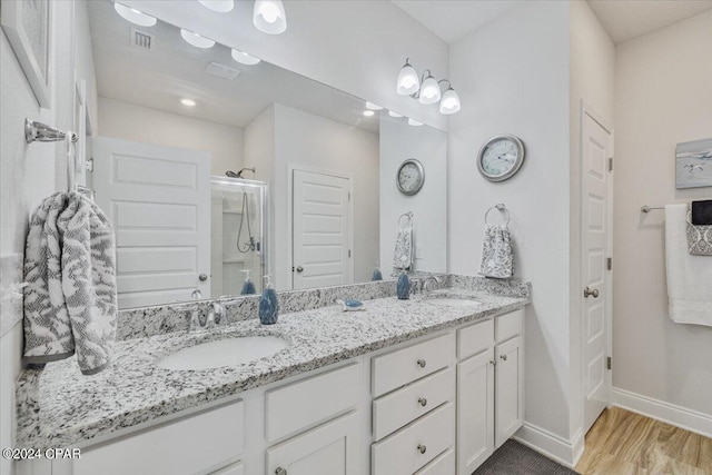 full bathroom featuring baseboards, visible vents, double vanity, a sink, and a shower stall