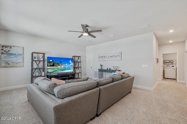 living room with washer / dryer, light carpet, a ceiling fan, and a textured ceiling