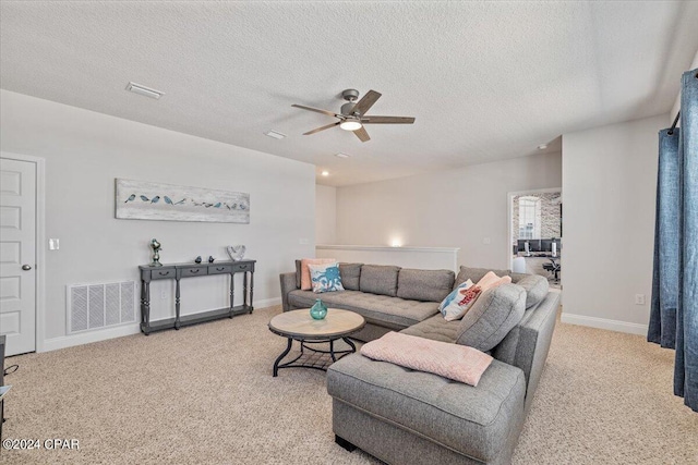 carpeted living room with a ceiling fan, baseboards, visible vents, and a textured ceiling