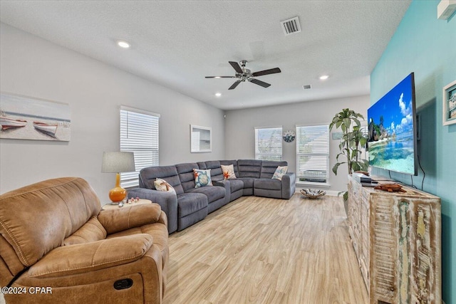 living room with ceiling fan, a textured ceiling, and light hardwood / wood-style floors