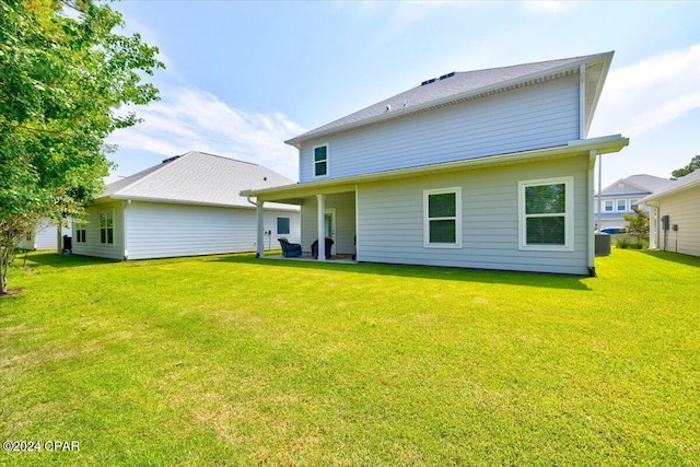 rear view of property featuring central air condition unit and a lawn