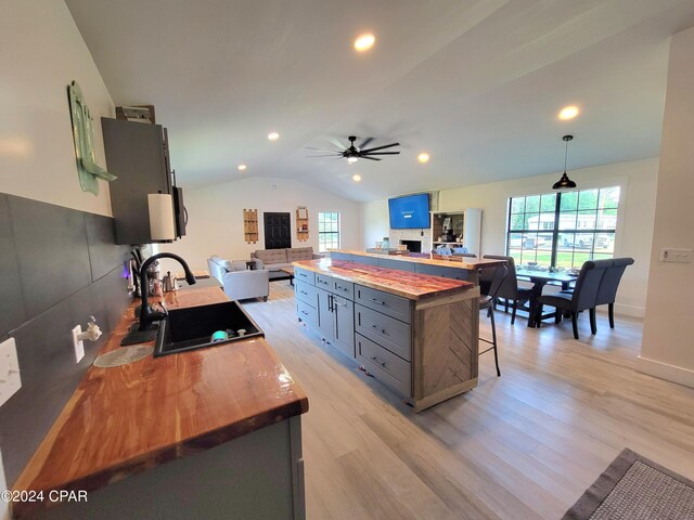 kitchen with a kitchen bar, butcher block countertops, lofted ceiling, and ceiling fan