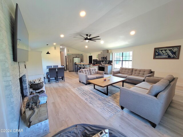 living room with ceiling fan, lofted ceiling, light hardwood / wood-style floors, and a fireplace