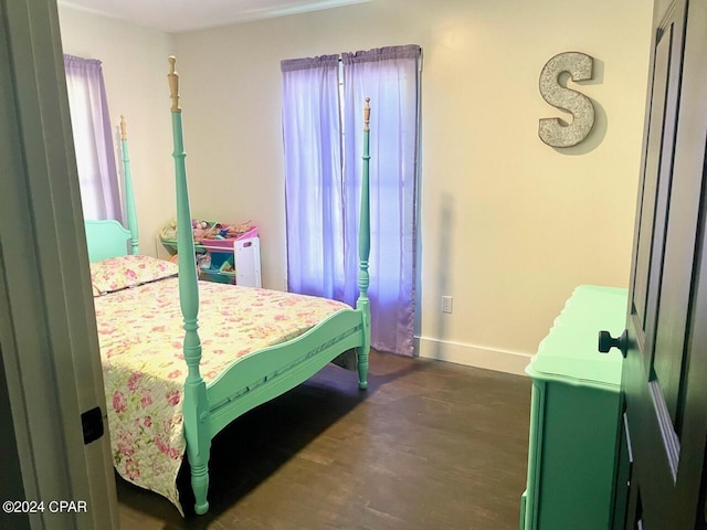 bedroom with baseboards and dark wood-type flooring