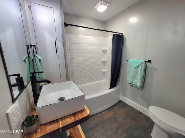 bathroom with baseboards, toilet, wood finished floors, shower / tub combo with curtain, and a sink